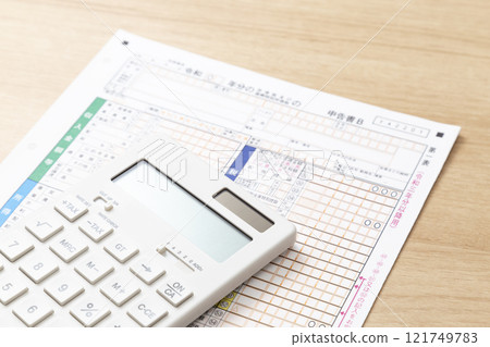 Tax return documents and a calculator on a desk 121749783