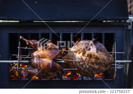 Roasting pork and turkey on spit Roasting pork and turkey on spit 121750257