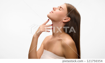 Side view photo of young attractive woman posing demonstrating her lift, smooth skin of neckline zone against white studio background. Concept of natural beauty. Side view photo of young attractive woman posing demonstrating her lift, smooth skin of neckline zone against white studio background. Concept of natural beauty. 121750354