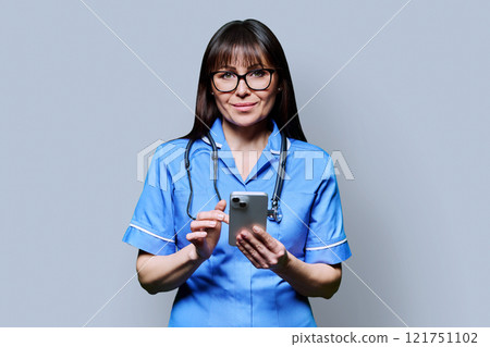 Portrait of smiling female nurse with smartphone, on grey studio background Portrait of smiling female nurse with smartphone, on grey studio background 121751102