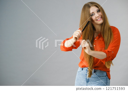 Woman combing her brown hair Woman combing her brown hair 121751593
