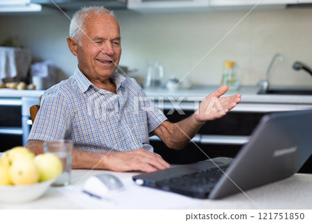 Old man with laptop talking through video call 121751850