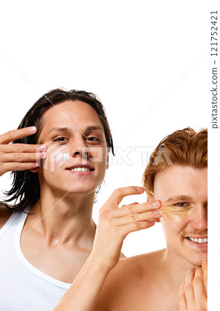 Collage. Young handsome men smiling and applying cream or under-eye patches against white background, shows skincare and inclusivity in beauty care. Collage. Young handsome men smiling and applying cream or under-eye patches against white background, shows skincare and inclusivity in beauty care. 121752421