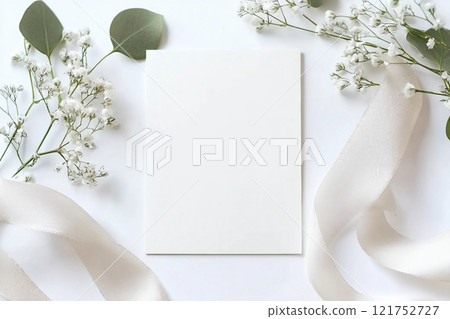 Styled stock photo. Feminine wedding desktop stationery mockup with blank greeting card, baby's breath Gypsophila flowers, dry green eucalyptus leaves, satin ribbon and white background. Empty space. 121752727