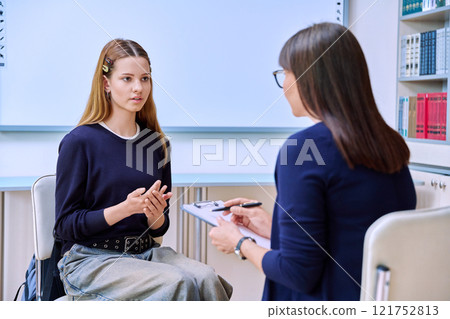 Sad serious teenage student girl talking with female school counselor, teacher 121752813