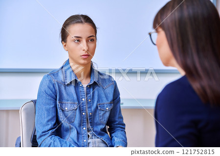 Female psychologist talking with teenage girl inside educational building 121752815