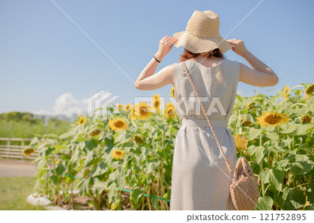 Woman in straw hat enjoying sunflower field 121752895