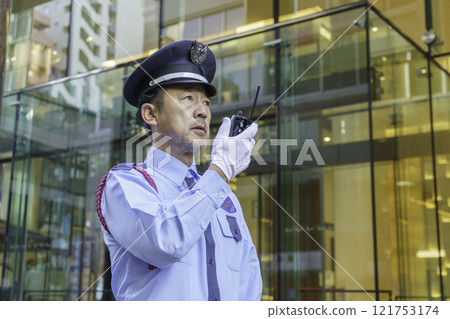 A middle-aged male security guard talking on a walkie-talkie. Photo courtesy of Denpa Gakuen, Tokyo Electronics College. 121753174