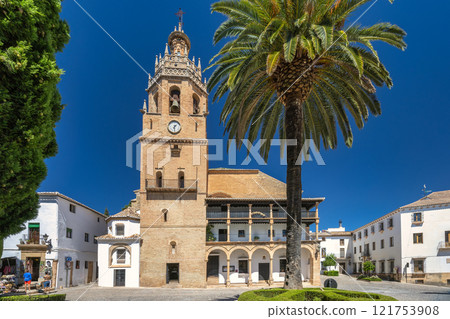 Ronda town in Spain. Historic town square with church and palm tree. Sunny day, traditional architecture. 121753908
