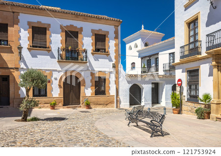 Ronda town in Spain. Charming town square with traditional architecture. Whitewashed buildings, stone streets, and wrought-iron benches create a peaceful atmosphere. 121753924