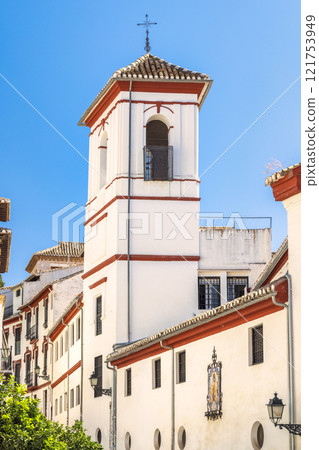 Granada town in Spain. White building with red trim and a bell tower against a clear blue sky. Traditional architecture. Granada town in Spain. White building with red trim and a bell tower against a clear blue sky. Traditional architecture. 121753949