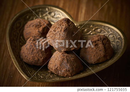 Chocolate truffles served in a heart-shaped container 121755035