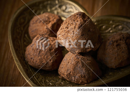 Chocolate truffles served in a heart-shaped container 121755036