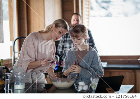 Family making pancakes for breakfast. Girl mixing, preparing pancake batter in the kitchen. 121756164