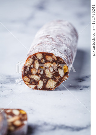 Chocolate salami with nuts on white background. Traditional Italian sweet sausage for Easter. Chocolate salami with nuts on white background. Traditional Italian sweet sausage for Easter. 121756241