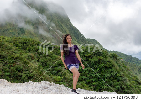 Portrait of a beautiful young Filipina woman against the background of a volcano covered with smog and clouds 121756898