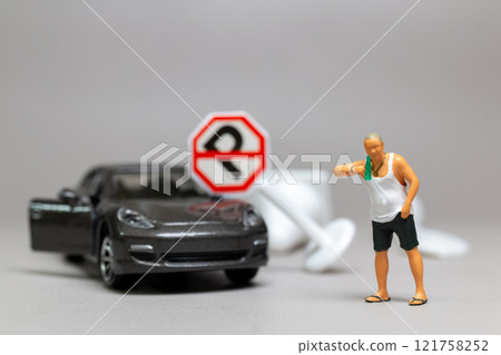 A Drunk driver holding a liquor bottle as he steps out of a car. concepts of reckless behavior, urban life A Drunk driver holding a liquor bottle as he steps out of a car. concepts of reckless behavior, urban life 121758252