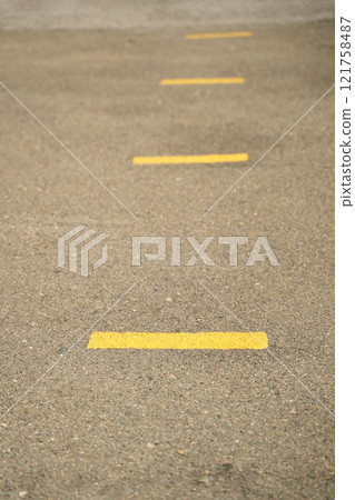 Close up view of yellow road lines on asphalt pavement for traffic safety Close up view of yellow road lines on asphalt pavement for traffic safety 121758487