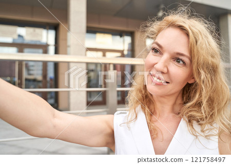 Smiling caucasian female adult taking a selfie outdoors with blonde hair Smiling caucasian female adult taking a selfie outdoors with blonde hair 121758497