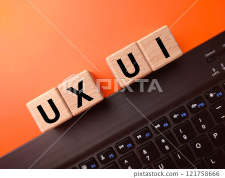 Keyboard and wooden block with the word UX UI on a orange background.User Interface and User Experience design concept. 121758666