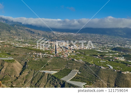 Beautiful landscape of a small agricultural village on a sunny afternoon near a highway or busy road for logistics or transport of goods. Banana plantations in the town of Los Llanos, La Palma, Spain Beautiful landscape of a small agricultural village on a sunny afternoon near a highway or busy road for logistics or transport of goods. Banana plantations in the town of Los Llanos, La Palma, Spain 121759034