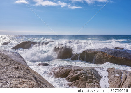 A rocky shore and a view of the ocean with waves, blue sky copy space, and a horizon in the background in Camps Bay, Cape Town, South Africa. Calm, serene, tranquil beach and nature scenery 121759066