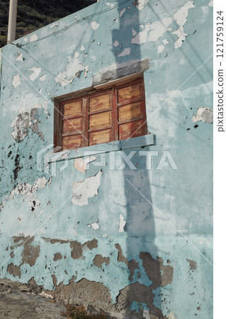 Architecture of an old blue wall with peeling paint outside. Exterior texture details of an old rustic residential build with vintage wooden shut windows discovered in Santa Cruz de La Palma Architecture of an old blue wall with peeling paint outside. Exterior texture details of an old rustic residential build with vintage wooden shut windows discovered in Santa Cruz de La Palma 121759124