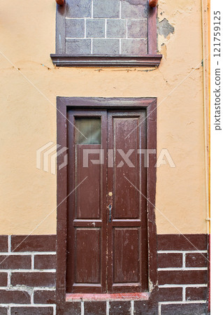 Old house or church with peeling paint on wall or window and wooden shutter door. Vintage and aged residential building built in a traditional architectural style or design in Santa Cruz de La Palma Old house or church with peeling paint on wall or window and wooden shutter door. Vintage and aged residential building built in a traditional architectural style or design in Santa Cruz de La Palma 121759125