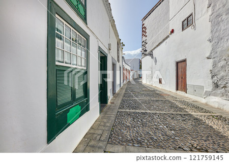 Scenic view of old historic houses, residential buildings, traditional infrastructure in cobblestone alleyway, street, road. Tourism abroad, overseas travel destination in Santa Cruz, La Palma, Spain 121759145