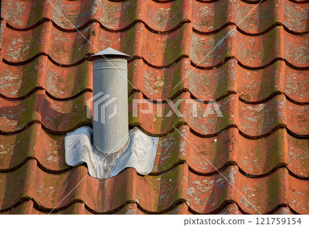 Air flow ventilation pillar and chimney on a slate roof of q house or factory building outside with copyspace. Construction of an exterior vent on rooftop for fireplace or oven smoke and heat control 121759154