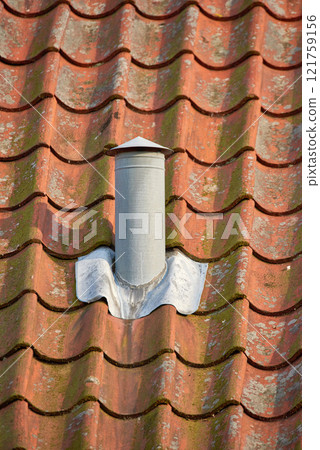 Ventilation pillar and chimney on rooftop of a house or factory building contributing to air pollution. Construction of an exterior chute for air flow with copyspace for cooling and heating control 121759156