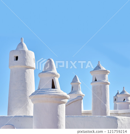 Traditional ventilation chimney on a roof isolated on blue sky background. Exterior of historical or ancient air tubes on rural white stone house or primitive building. Simple minimalist architecture Traditional ventilation chimney on a roof isolated on blue sky background. Exterior of historical or ancient air tubes on rural white stone house or primitive building. Simple minimalist architecture 121759214