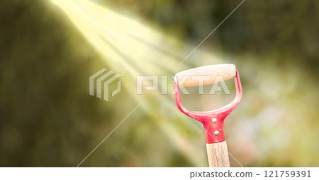 Sunlight shining on a shovel in a green garden outdoors in the backyard or garden of a house. Closeup of a wooden spade or gardening tool outside in a yard with blurred trees in the background Sunlight shining on a shovel in a green garden outdoors in the backyard or garden of a house. Closeup of a wooden spade or gardening tool outside in a yard with blurred trees in the background 121759391