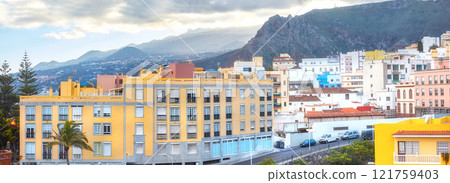 Scenic landscape view of vibrant houses, traditional residential buildings or city structures. Tourism destination street on Santa Cruz road, La Palma, Spain with background mountains and cloudy sky 121759403