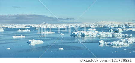 Beautiful landscape of the sea with ice on a cold winter day with a blue sky with copy space. Small iceberg in the ocean outdoors in nature in the North Atlantic with copyspace 121759521