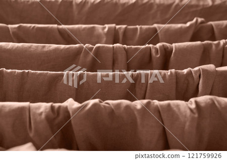 Close up textured brown fabric folds creating ripples and shadows in light 121759926
