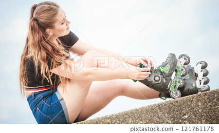 Happy young woman wearing roller skates 121761178