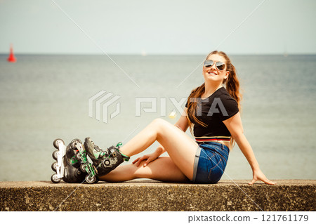 Happy young woman wearing roller skates Happy young woman wearing roller skates 121761179