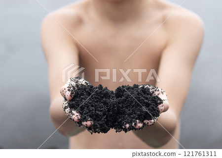 Teenager is holding a handful of black sand in Hawaii beach. 121761311