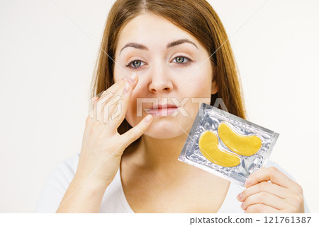 Woman ready to apply gold eye patches Woman ready to apply gold eye patches 121761387