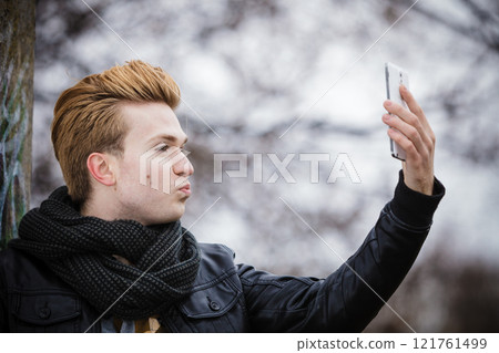 guy taking self picture with phone outdoors 121761499