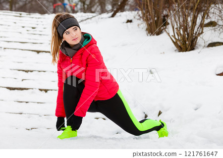 Woman wearing sportswear exercising outside during winter Woman wearing sportswear exercising outside during winter 121761647
