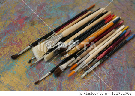 pile of artist brushes and an old palette  121761702