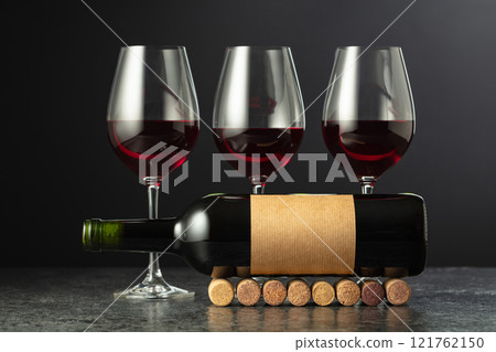 Bottle and glasses of red wine on a black stone table. Bottle and glasses of red wine on a black stone table. 121762150