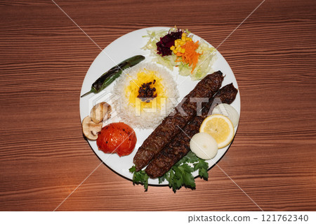 Turkish kebab plate with rice and salad on wooden background. Retro flash food photography Turkish kebab plate with rice and salad on wooden background. Retro flash food photography 121762340