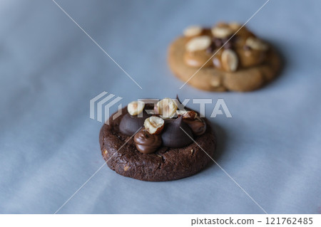 Homemade american dark chocolate cookie with chocolate cream and hazelnut topping with peanut butter cookie on background. Homemade american dark chocolate cookie with chocolate cream and hazelnut topping with peanut butter cookie on background. 121762485