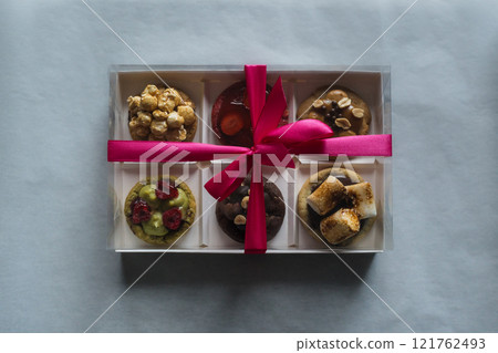 Festive decorated american homemade cookies with toppings in a gift box with ribbon. Berries, pistachio, caramel, marshmallow, peanuts, chocolate Festive decorated american homemade cookies with toppings in a gift box with ribbon. Berries, pistachio, caramel, marshmallow, peanuts, chocolate 121762493