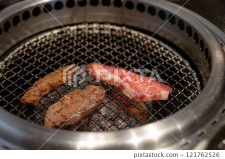 Grilled meat on barbecue grill, close up. Concept of cooking, barbecue, and traditional japanese yakiniku dining experience. 121762526