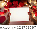 Woman hands holding a white blank valentine's day invitation mockup, Valentine's day scene in the background  121762597