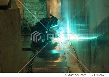 Welding sparks illuminate workshop as craftsman creates metal structure 121762676